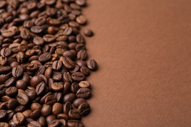 Photo of Aromatic coffee beans on brown background, closeup. Space for text