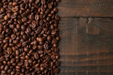 Photo of Aromatic coffee beans on wooden table, top view. Space for text