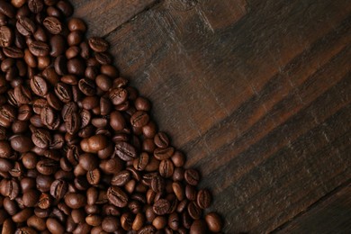 Photo of Aromatic coffee beans on wooden table, top view. Space for text
