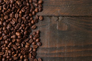 Photo of Aromatic coffee beans on wooden table, top view. Space for text