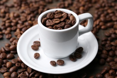 Photo of Aromatic coffee beans, cup and saucer on table, closeup