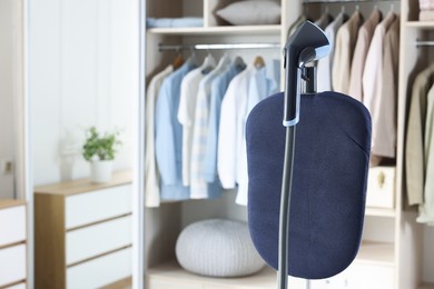 Photo of Modern upright steamer with stand near wardrobe indoors