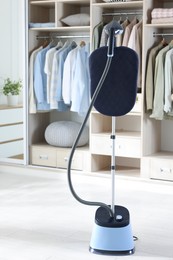 Photo of Modern upright steamer with stand and wardrobe indoors