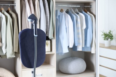 Photo of Modern upright steamer with stand near wardrobe indoors