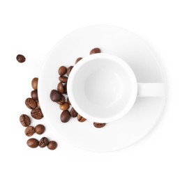 Photo of Aromatic coffee beans, cup and saucer isolated on white, top view