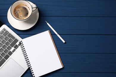 Photo of Notebook with pen, laptop and coffee on blue wooden table, flat lay. Space for text