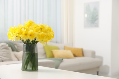 Photo of Beautiful daffodils in vase on white table at home, space for text