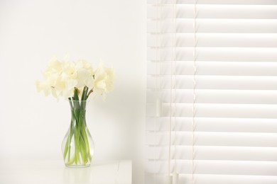 Photo of Beautiful daffodils in vase on white table at home, space for text