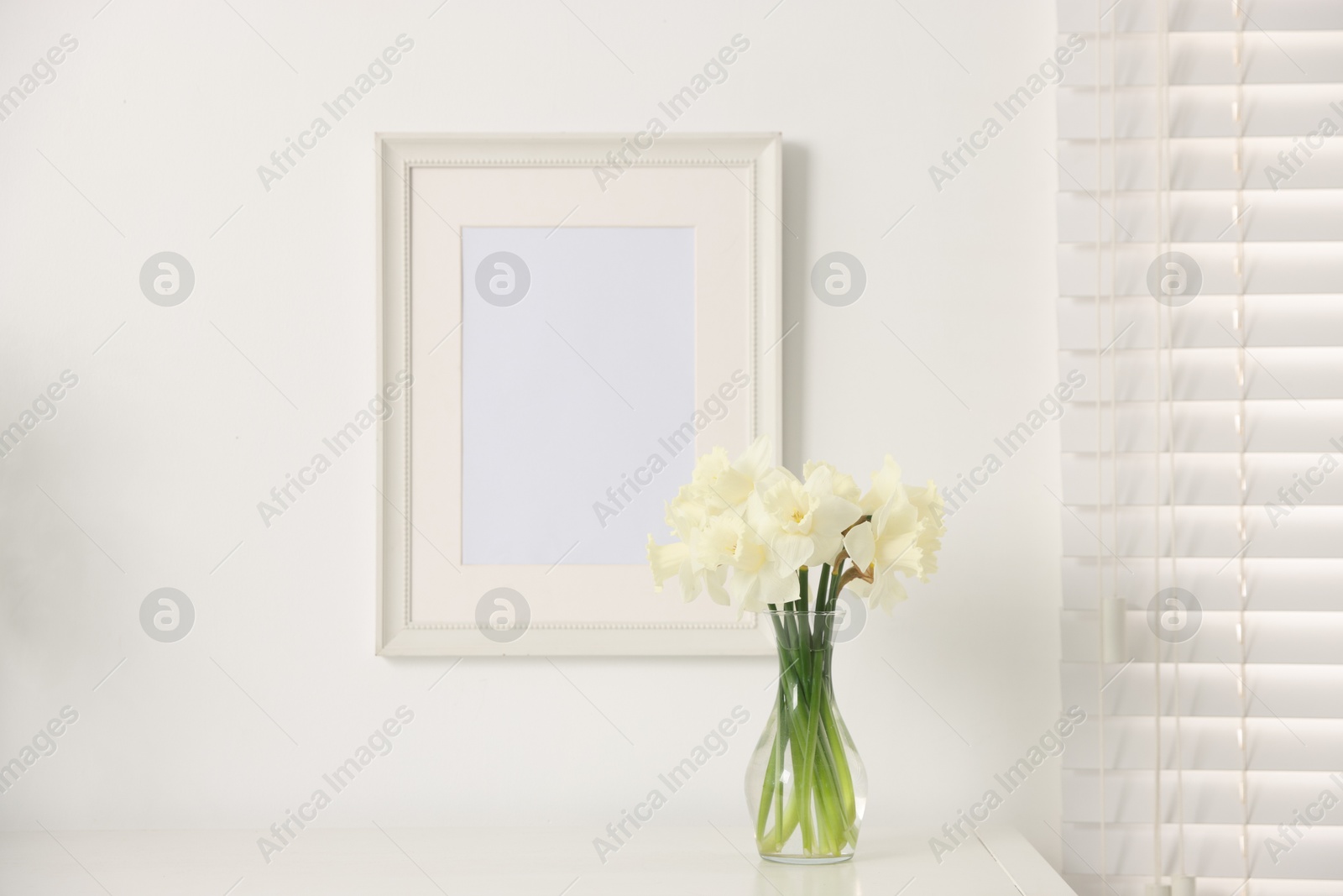 Beautiful daffodils in vase on white table at home Photo of Beautiful daffodils in vase on white table at home