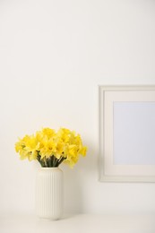Photo of Beautiful daffodils in vase on white table at home