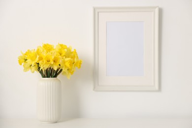 Photo of Beautiful daffodils in vase on white table at home