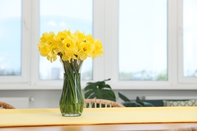 Photo of Beautiful daffodils in glass vase on table at home, space for text