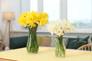 Photo of Beautiful daffodils in glass vases on table at home