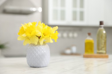 Photo of Beautiful daffodils in vase on white marble table indoors, space for text