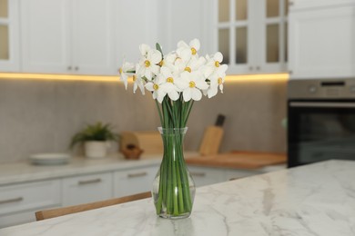 Photo of Beautiful daffodils in vase on white marble table indoors
