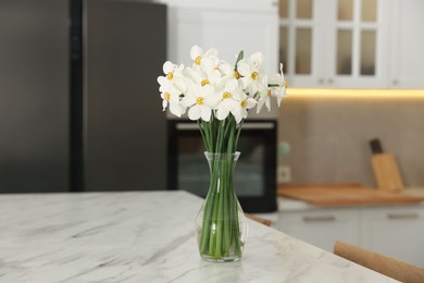 Photo of Beautiful daffodils in vase on white marble table indoors