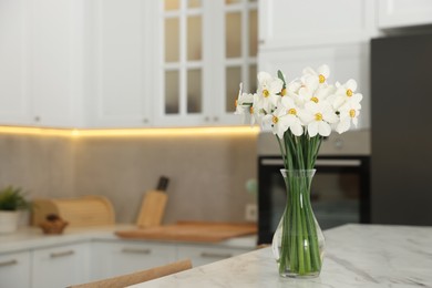 Photo of Beautiful daffodils in vase on white marble table indoors, space for text
