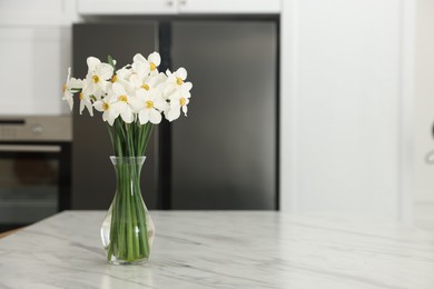 Photo of Beautiful daffodils in vase on white marble table indoors, space for text