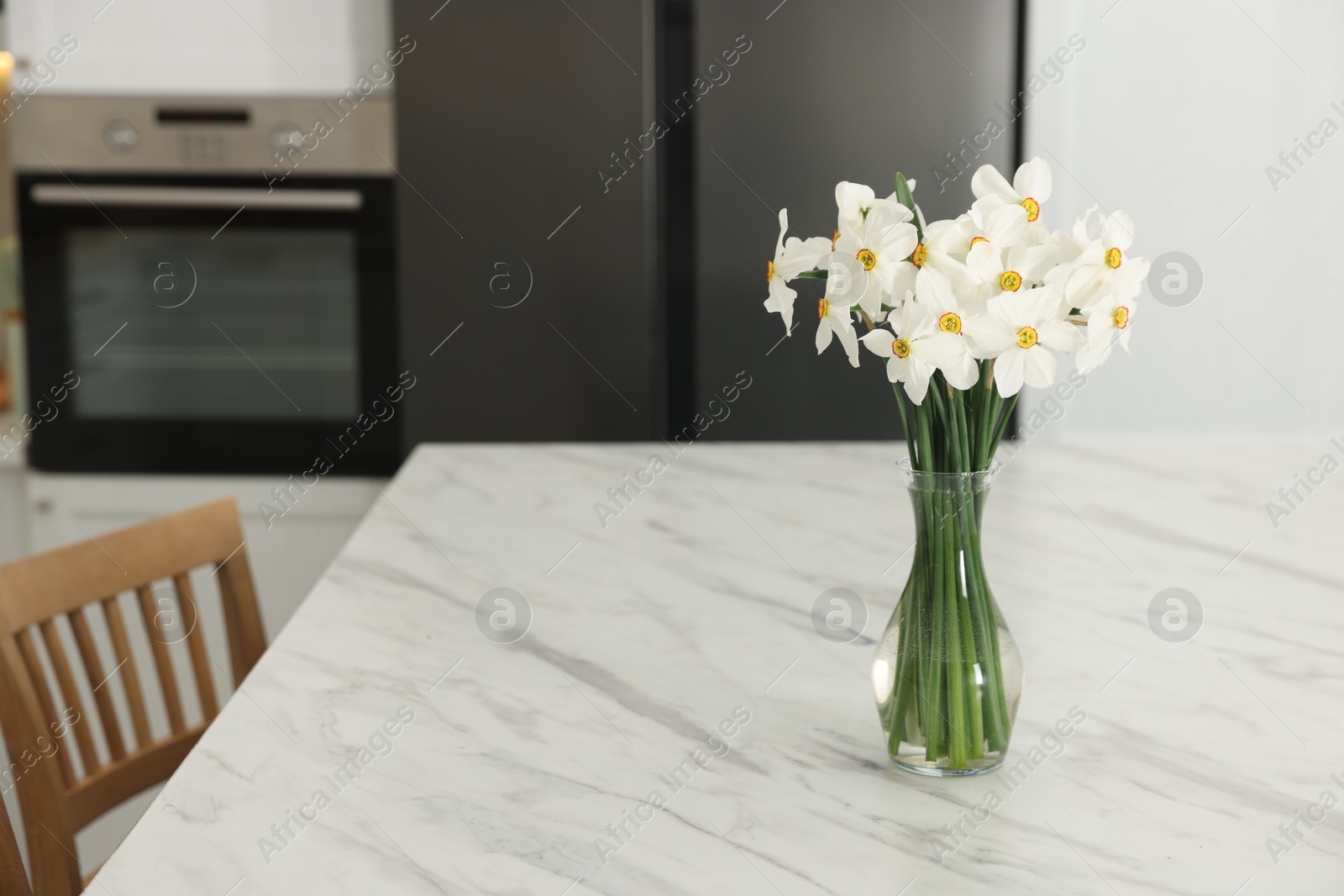 Beautiful daffodils in vase on white marble table indoors, space for text Photo of Beautiful daffodils in vase on white marble table indoors, space for text