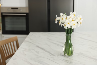Photo of Beautiful daffodils in vase on white marble table indoors, space for text