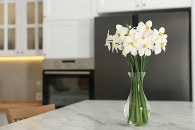 Photo of Beautiful daffodils in vase on white marble table indoors, space for text