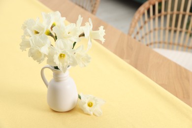 Photo of Beautiful daffodils in vase on table at home, space for text