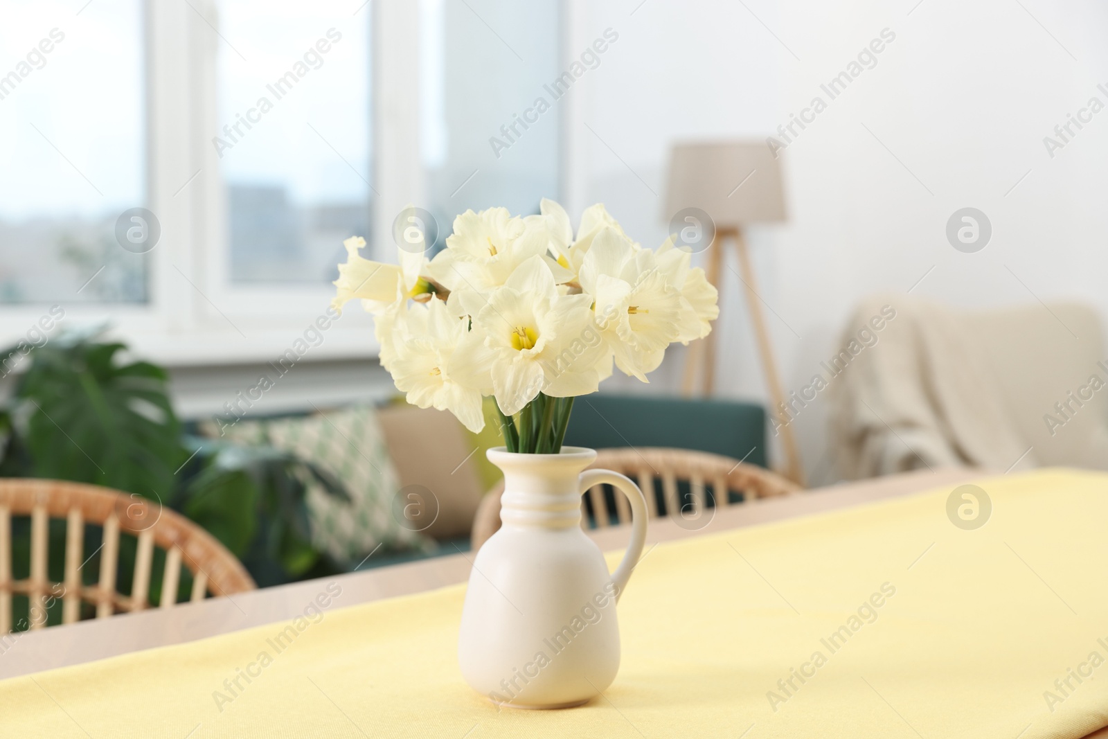 Beautiful daffodils in vase on table at home Photo of Beautiful daffodils in vase on table at home