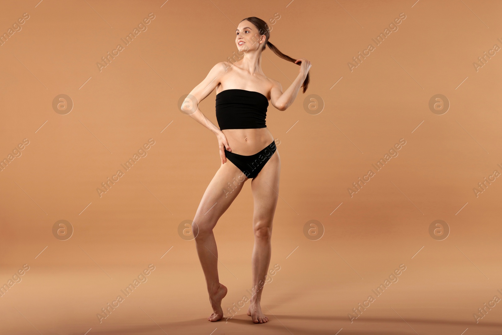 Beautiful woman with perfect slim body on beige background Photo of Beautiful woman with perfect slim body on beige background