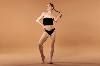 Photo of Beautiful woman with perfect slim body on beige background