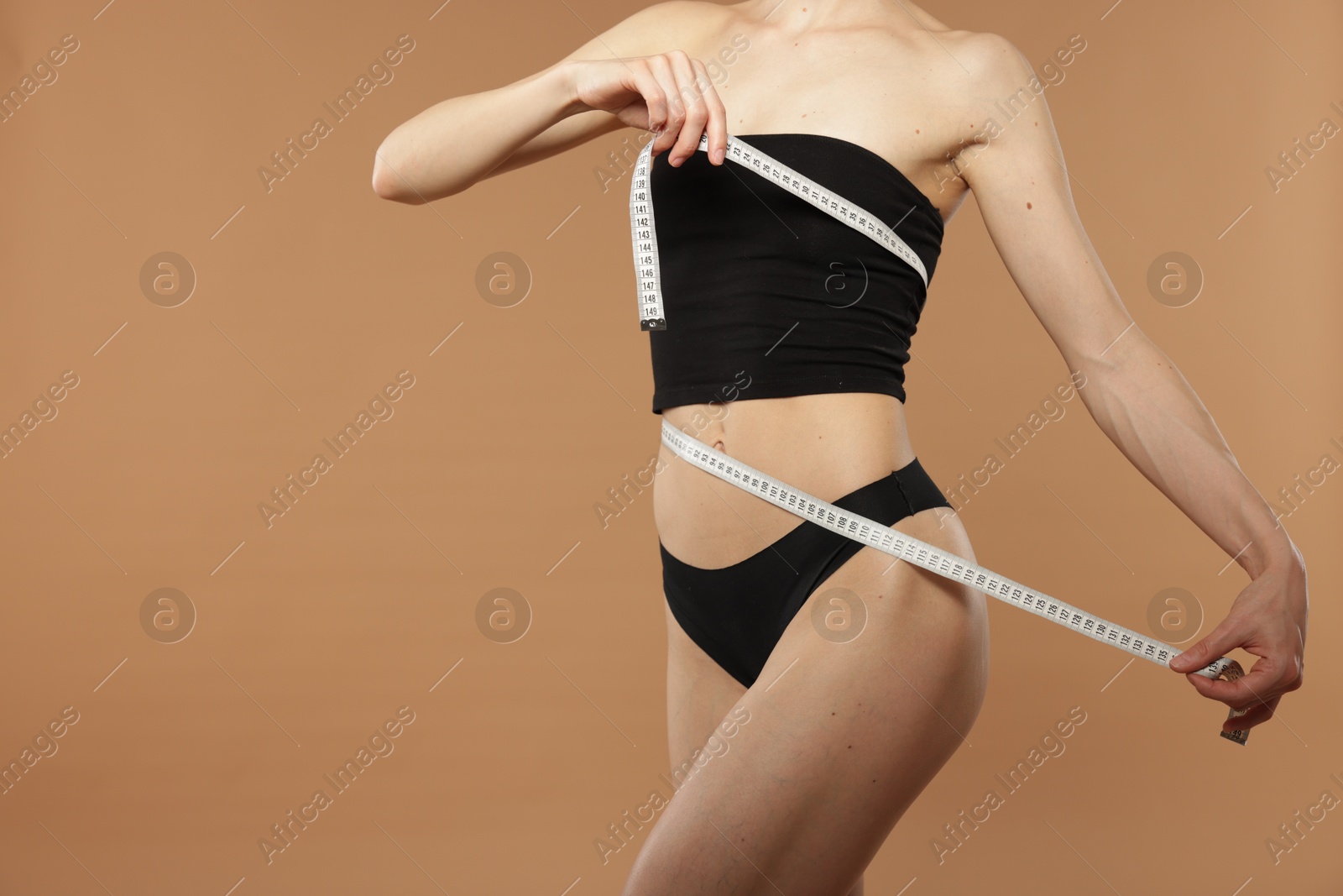 Woman with slim body and measuring tape on beige background, closeup. Space for text Photo of Woman with slim body and measuring tape on beige background, closeup. Space for text