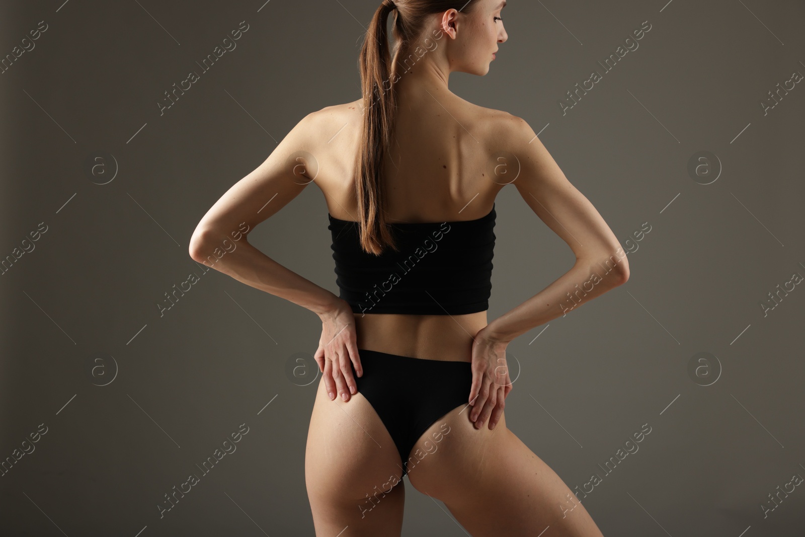 Photo of Woman with perfect slim body on grey background, back view