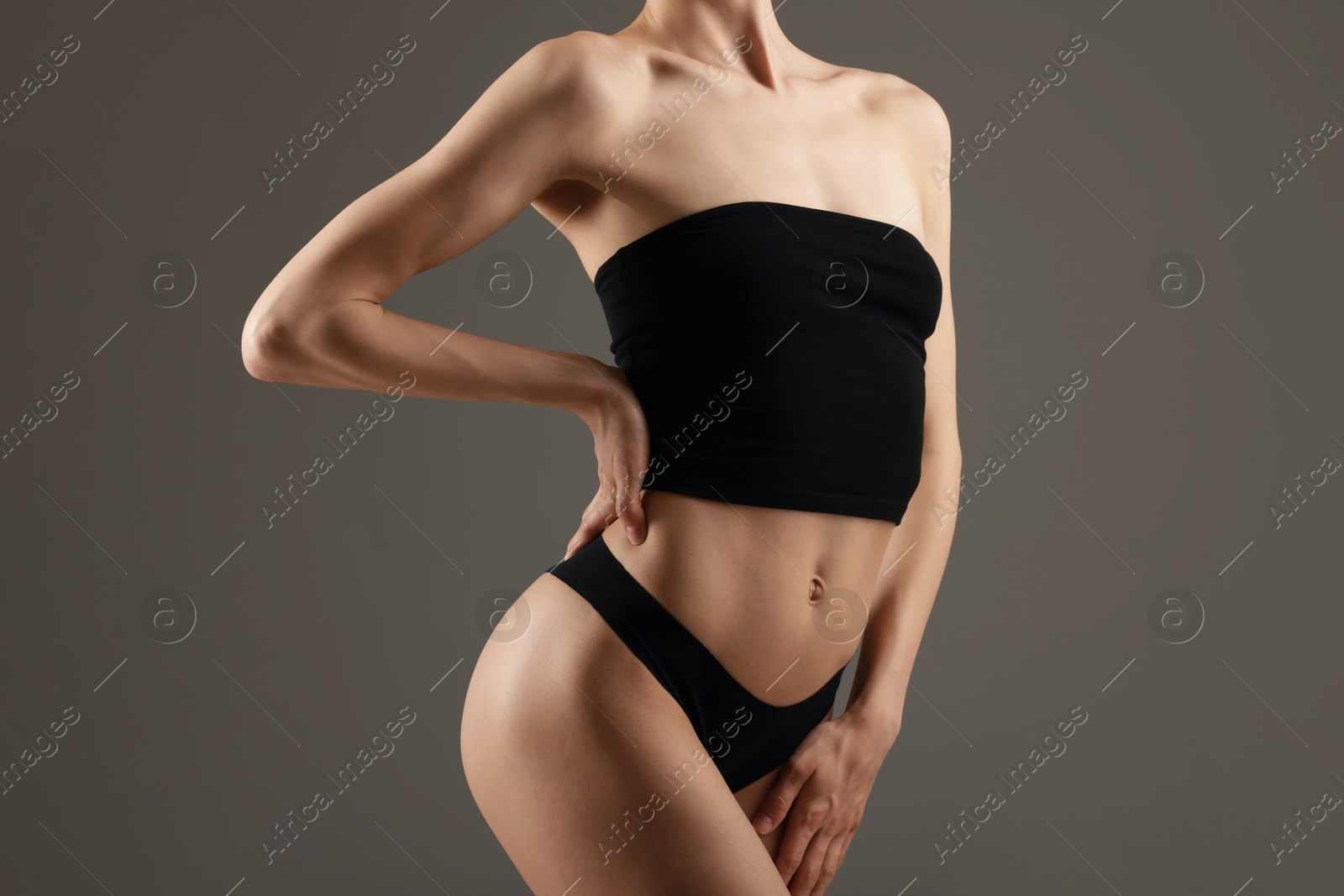 Photo of Woman with perfect slim body on grey background, closeup