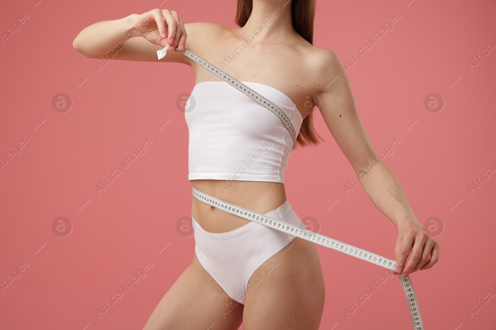 Photo of Woman with slim body and measuring tape on pink background, closeup