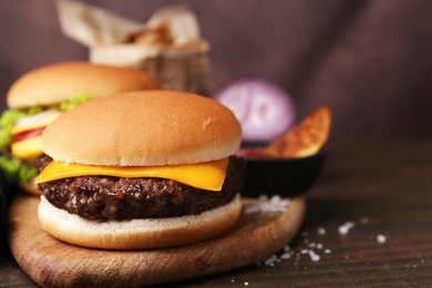 Photo of Tasty cheeseburgers on wooden table, closeup. Space for text