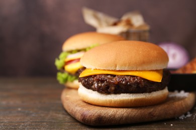 Photo of Tasty cheeseburgers on wooden table, closeup. Space for text