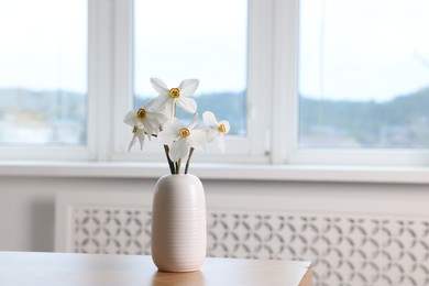 Photo of Beautiful daffodils in vase on wooden table at home. Space for text