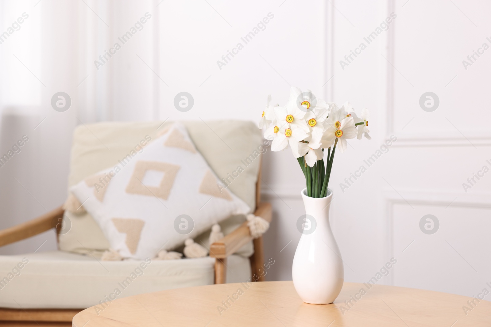 Beautiful daffodils in vase on wooden table at home. Space for text Photo of Beautiful daffodils in vase on wooden table at home. Space for text