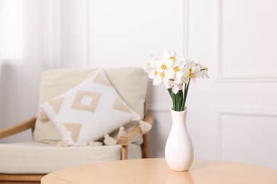 Photo of Beautiful daffodils in vase on wooden table at home. Space for text