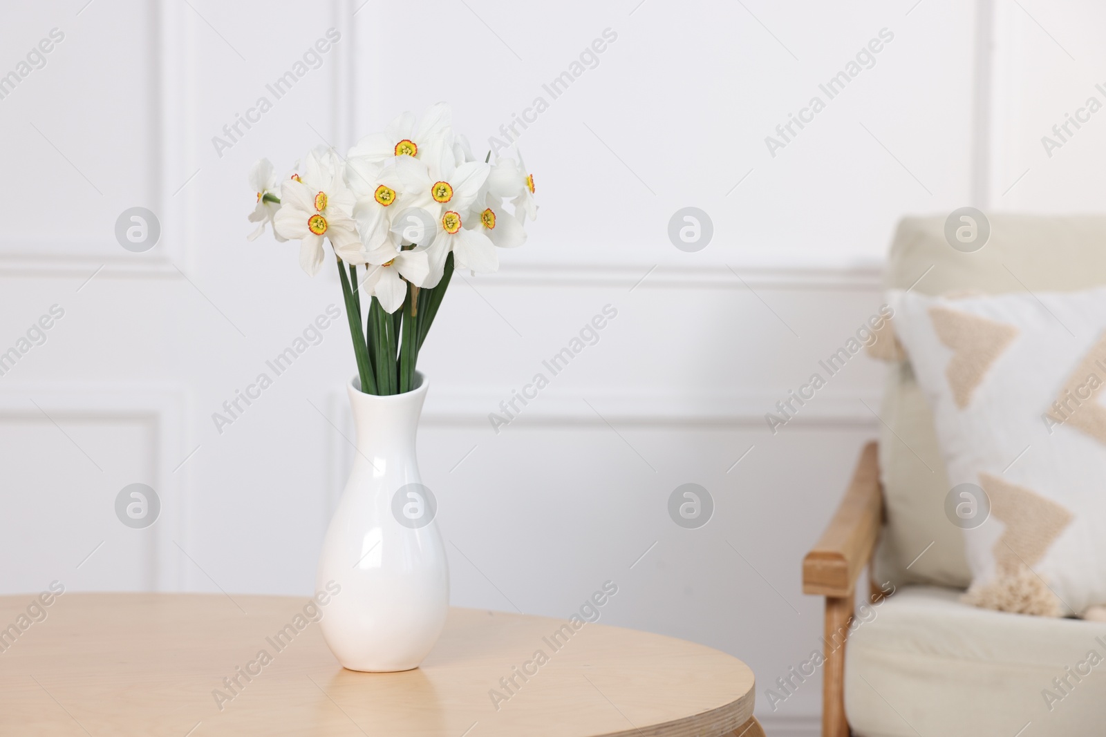 Beautiful daffodils in vase on wooden table at home. Space for text Photo of Beautiful daffodils in vase on wooden table at home. Space for text