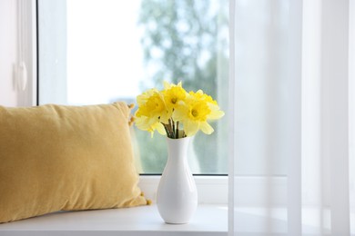 Photo of Beautiful daffodils in vase on windowsill at home