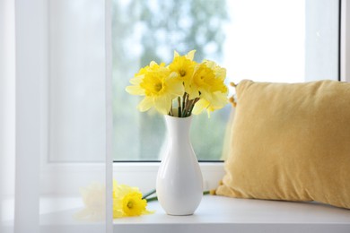 Photo of Beautiful daffodils in vase on windowsill at home