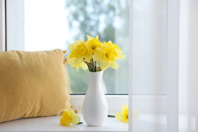Photo of Beautiful daffodils in vase on windowsill at home