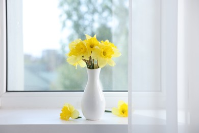 Photo of Beautiful daffodils in vase on windowsill at home