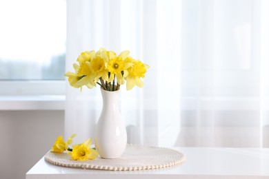 Photo of Beautiful daffodils in vase on white table at home. Space for text