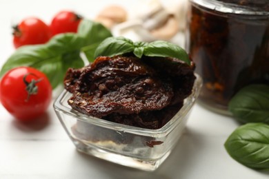 Photo of Delicious sun dried tomatoes, fresh vegetables and basil on white table, closeup