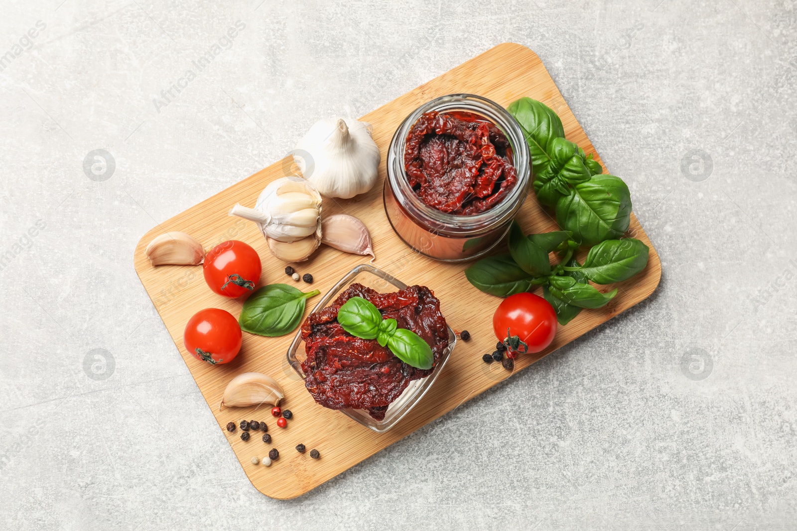 Delicious sun dried tomatoes, fresh vegetables, basil and garlic on light grey table, top view Photo of Delicious sun dried tomatoes, fresh vegetables, basil and garlic on light grey table, top view