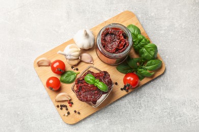 Photo of Delicious sun dried tomatoes, fresh vegetables, basil and garlic on light grey table, top view