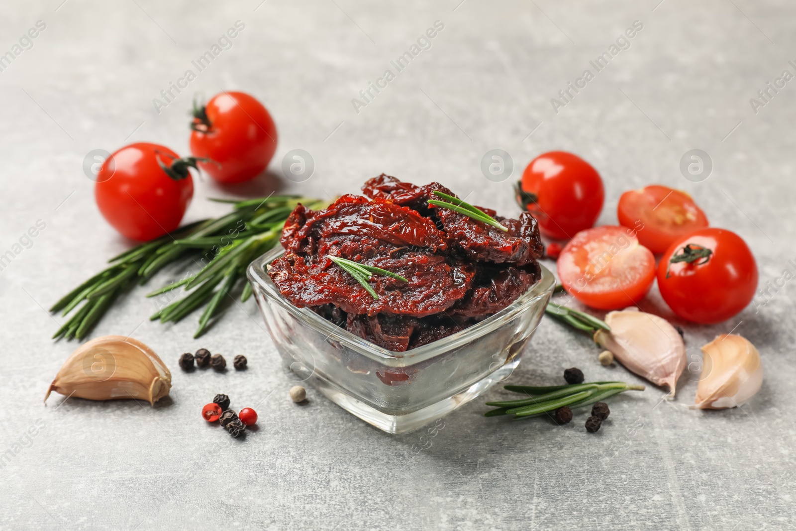 Delicious sun dried tomatoes, fresh vegetables, rosemary and garlic on light grey table Photo of Delicious sun dried tomatoes, fresh vegetables, rosemary and garlic on light grey table