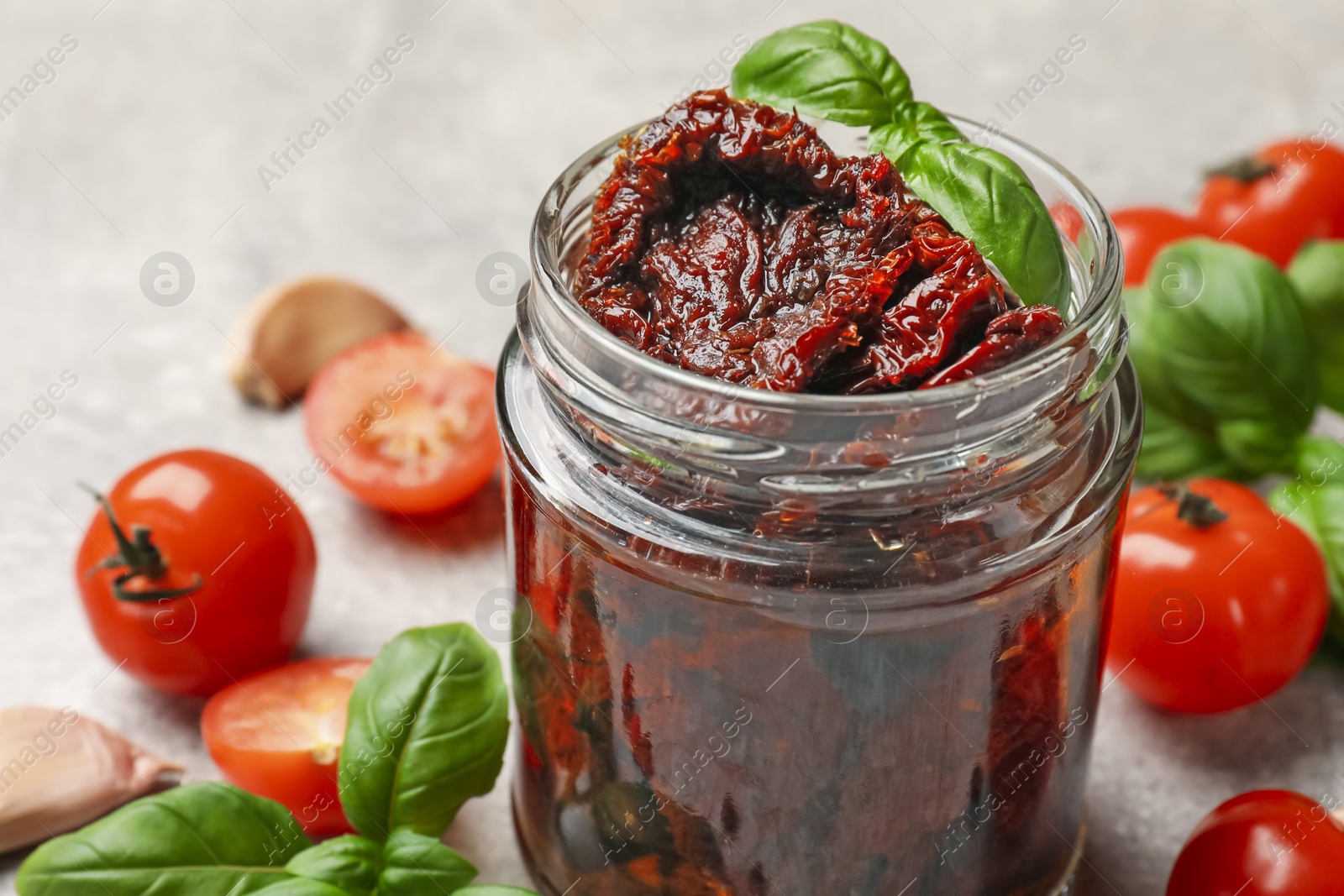 Delicious sun dried tomatoes, fresh vegetables, basil and garlic on light grey table, closeup Photo of Delicious sun dried tomatoes, fresh vegetables, basil and garlic on light grey table, closeup