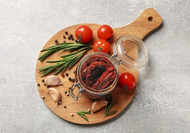 Photo of Delicious sun dried tomatoes, fresh vegetables, rosemary and garlic on light grey table, top view